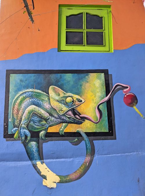 A wall mural of a chameleon sticking the tongue out and licking a red lolipop at Kampung Warna Warni Jodipan, Malang, Indonesia