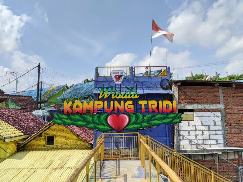 A sign of Wisata Kampung Tridi at the end of a yellow bridge in Malang, Indonesia