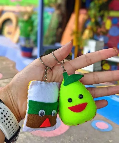Two keychains, one square with googly eyes and one green pear, given as gifts at Wisata Kampung Tridi, Malang, Indonesia