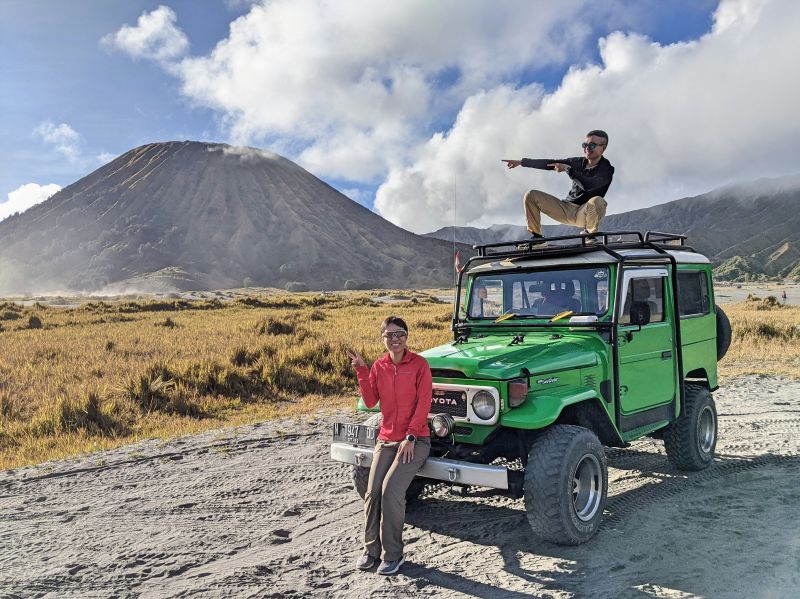 Jackie Szeto and Justin Huynh, Life Of Doing, sit and stand on the green Jeep with Bromo crater in the background