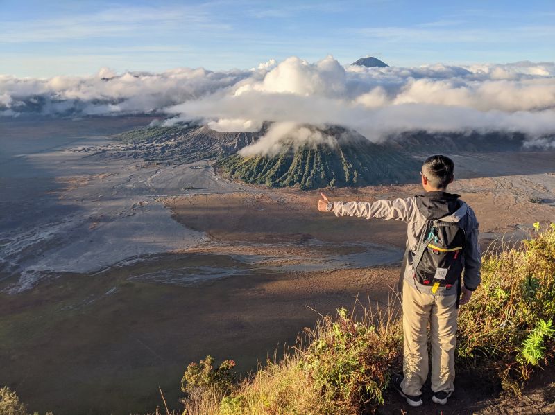 Justin Huynh, Life Of Doing, sticks out arm and holds a thumbs up with Bromo volcanoes in the background