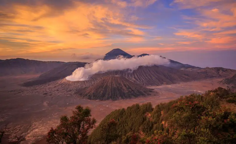 Purple and orange skies surround the Mount Bromo crater in East Java, Indonesia, one of the top places to visit on the East Java itinerary