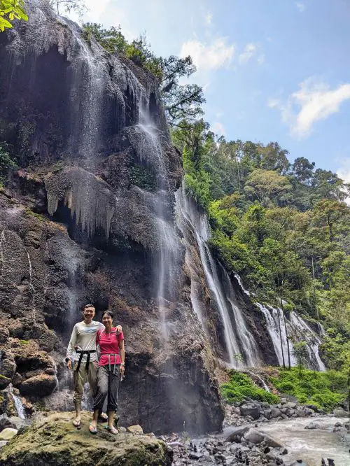 Justin Huynh and Jackie Szeto, Life Of Doing, stand in front of Goa Tetes Waterfall in Indonesia