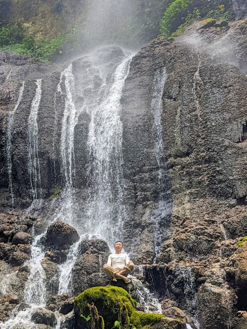 Justin Huynh, Life Of Doing, sit on a rock underneath a waterfall