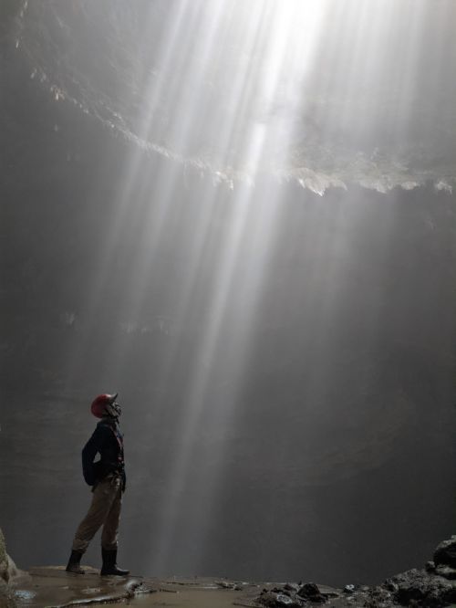 Justin Huynh, Life Of Doing, looks at the top of the cave opening to see the rays in Jomblang Cave