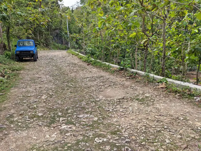 A blue Jeep parked along the stone road heading to Timang Beach, Indonesia