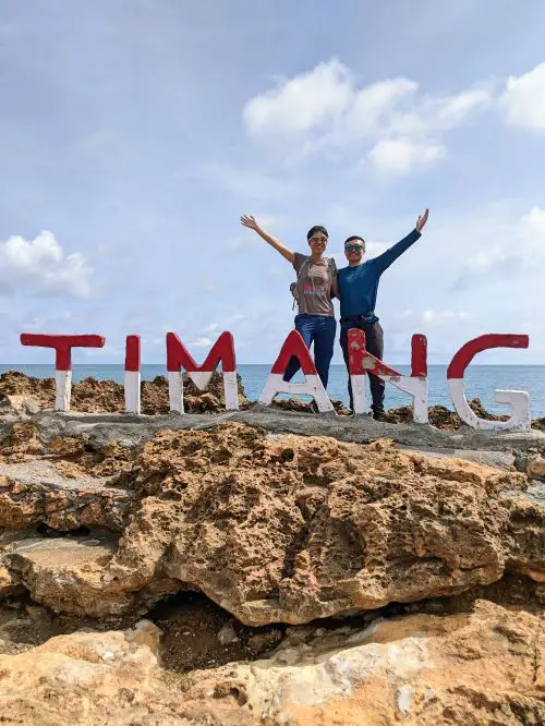 Jackie Szeto and Justin Huynh, Life Of Doing, stand next to the Timang sign on Timang Island, Indonesia
