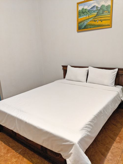 A bed with white sheets at Yanto Homestay, Indonesia