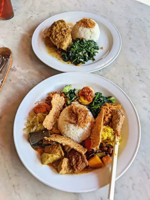 One plate of nasi campur, rice with meat and veggie sides and another plate of tuna with rice and veggies at Made Warung Seminyak