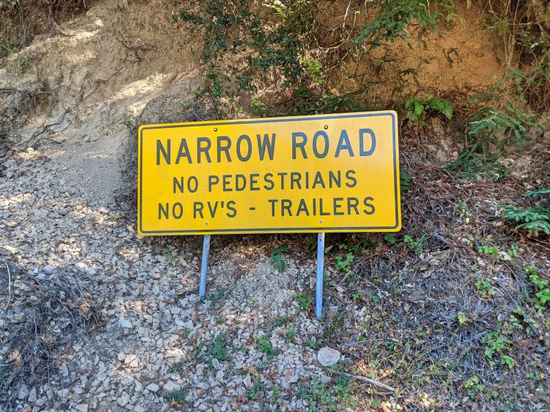 A yellow sign, "Narrow Road, no pedestrians, no RVs and trailers" that leads to the Pfeiffer Beach entrance
