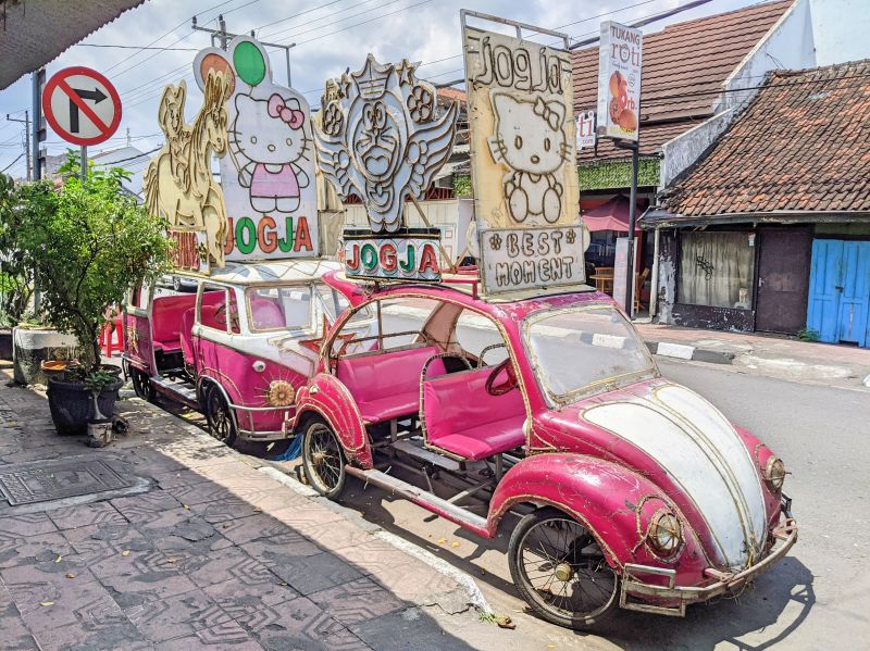 Pink Volkswagen Beetle cars with Hello Kitty and Doraemon signs