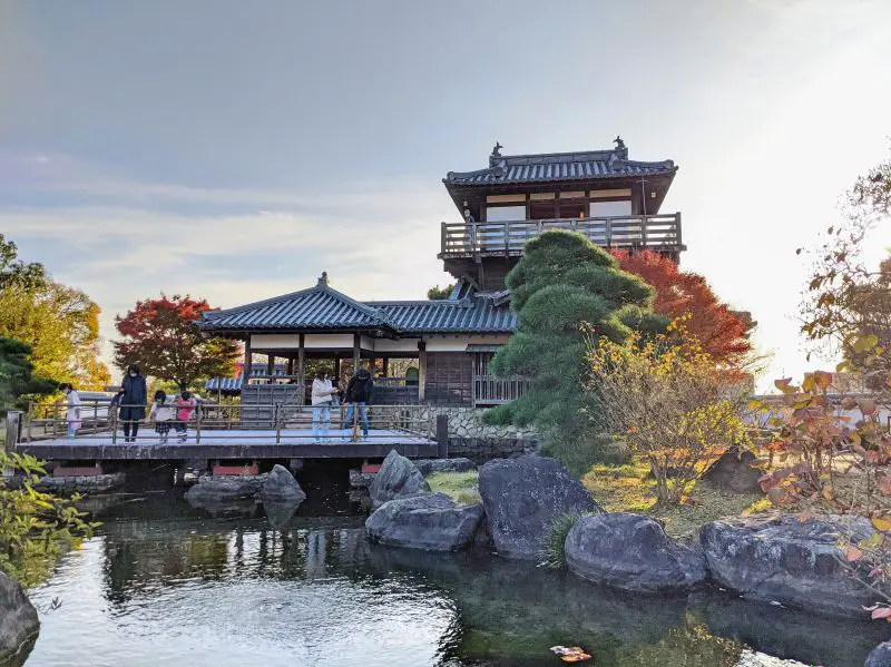 A restored castle at Ikeda Castle Park with a koi pond and a deck for visitors