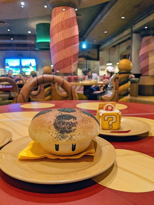 One plate has a bread topping covering a bowl and another plate has a question box tiramisu at Kinopio's Cafe, Super Nintendo World at Universal Studios Japan