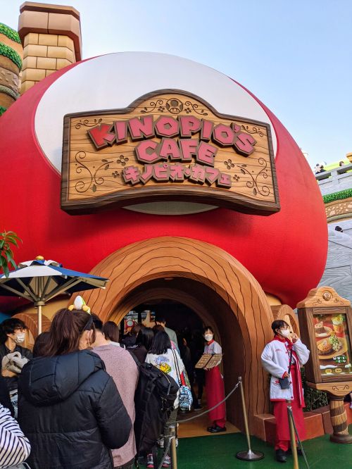 People waiting in line to enter the red and white mushroom shaped cafe called Kinopio's Cafe at Super Nintendo World, Universal Studios Japan