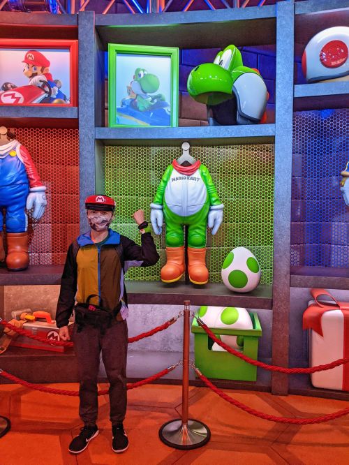 Justin Huynh, Life Of Doing, wears the Mario VR headset and poses next to the Yoshi dinosaur outfit at Super Nintendo World, Universal Studios Japan