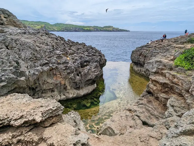 A pool of water in between rocky cliffsides at Angel's Billabong, Nusa Penida