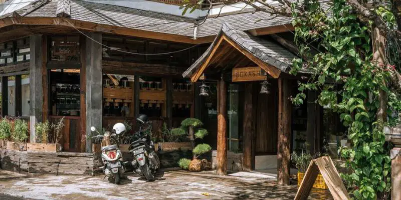 Two motorbikes parked in front of the Bokashi Cafe entrance in Canggu, Bali