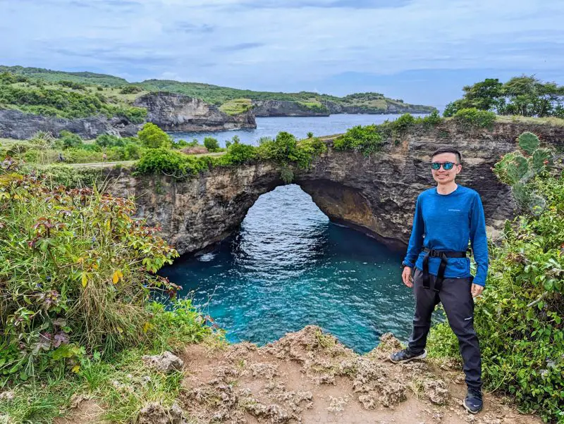 Justin Huynh, Life Of Doing, stands next Broken Beach archway in Nusa Penida