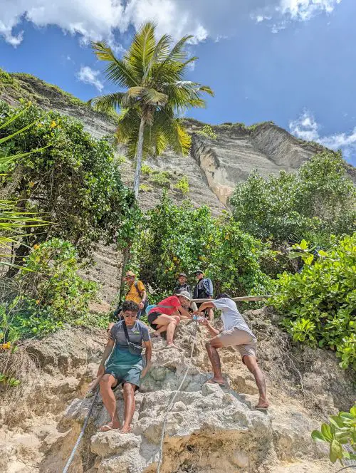 Six people using the rope to rappel down a rocky section to go to Diamond Beach, Nusa Penida, Indonesia