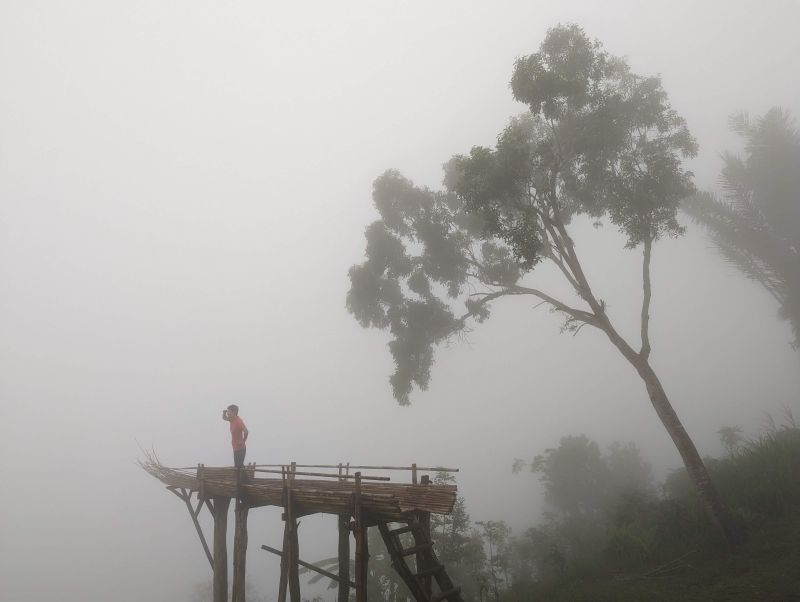 Jackie Szeto, Life Of Doing, stand on a wooden boat in the fog at Lahangan Sweet in Bali