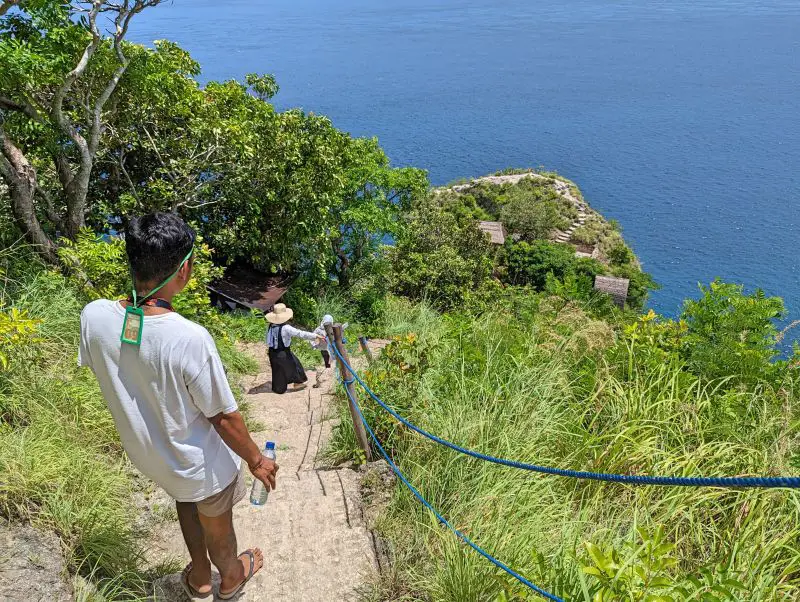 A man and two ladies walk down the steep staircase to reach Nusa Penida's Rumah Pohon treehouse