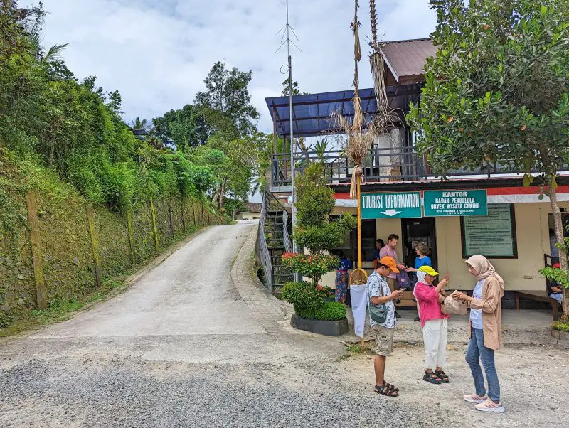 A handful of tourists stand in front of the Tegallalang Rice Terraces tourist information booth