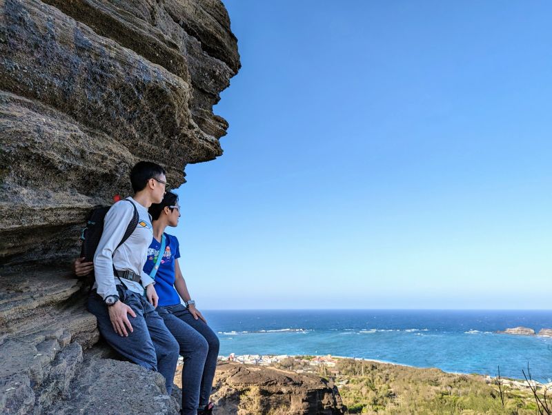 Jutin Huynh and Jackie Szeto, Life Of Doing, sit on a rock and look at blue ocean at Cao Cat Mountain, Phu Quy