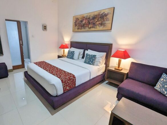 A bed with a purple sofa in Dikubu Belong Seminyak, a cheap place to stay in Seminyak, Bali
