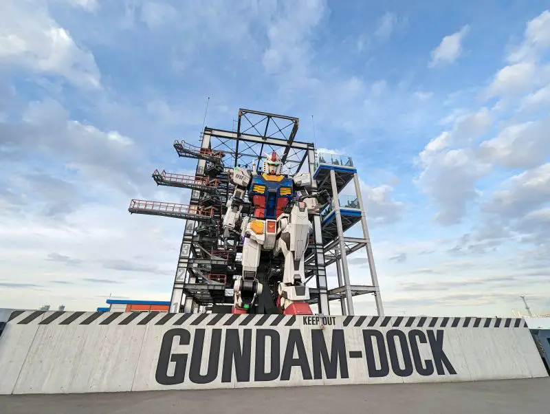 A giant Gundam robot kneeling down on the Gundam Dock at Gundam Factory in Yokohama