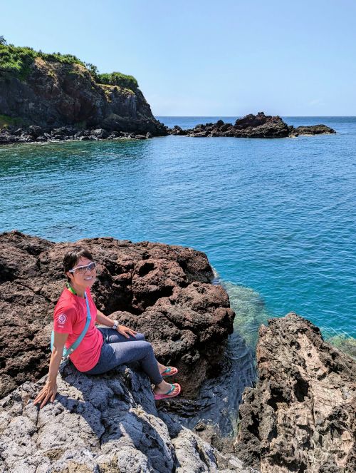 Jackie Szeto, Life Of Doing, sit on a rock with the turquoise ocean water in the background on Hon Tranh Island, Vietnam