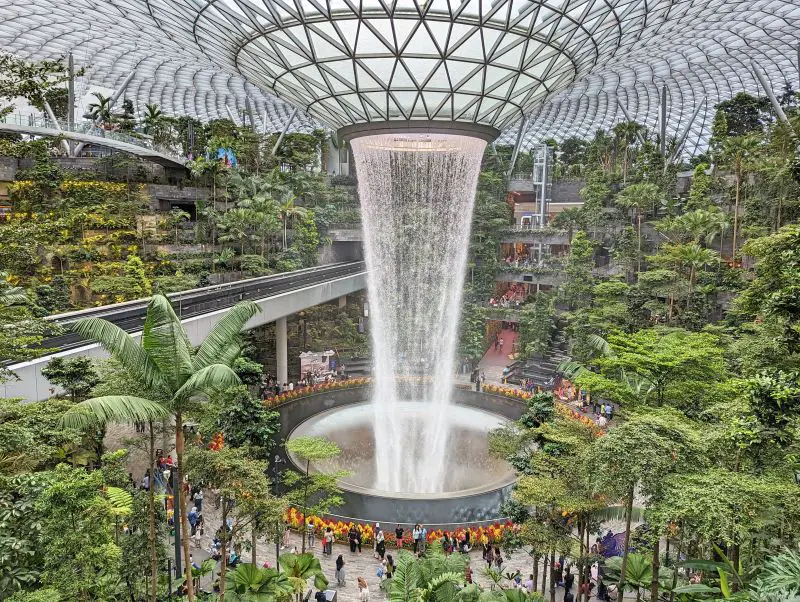 An indoor waterfall called Rain Vortex surrounded by trees and plants at the Jewel Changi Airport, Singapore