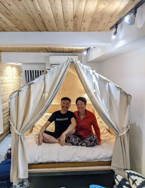 Justin Huynh and Jackie Szeto, Life Of Doing, sit inside their glamping bed in their Tokyo Airbnb