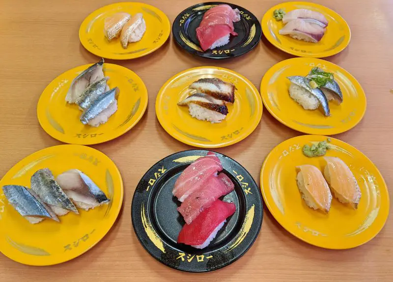 Seven yellow plates of sushi and two black plates of tuna nigiri at Sushiro Sushi in Japan