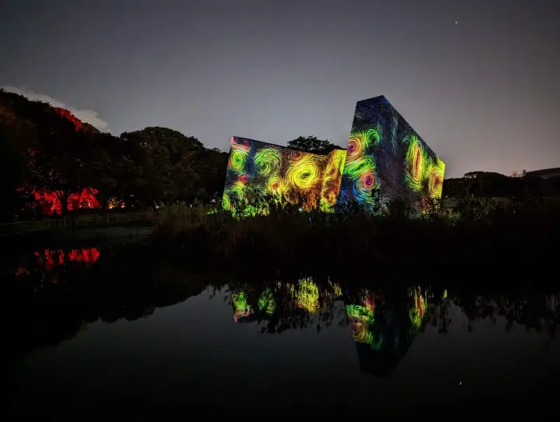 Three panels in the middle of the lake displaying colorful swirls at TeamLab Botanical Garden Osaka