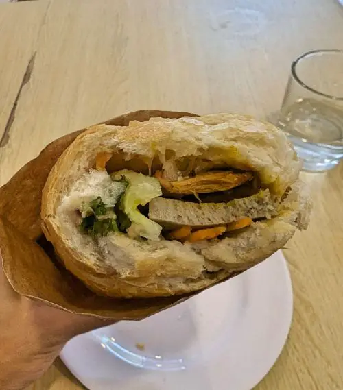 Inside of an eaten vegan banh mi sandwich with beancurd, faux meats, carrots, and vegetables at Banh Mi Vegan in Hanoi, Vietnam