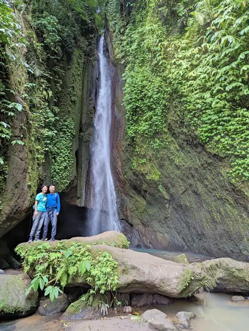 Jackie Szeto and Justin Huynh, Life Of Doing, stands on a rock next to the gentle cascades of Leke Leke Waterfall in Bali, Indonesia