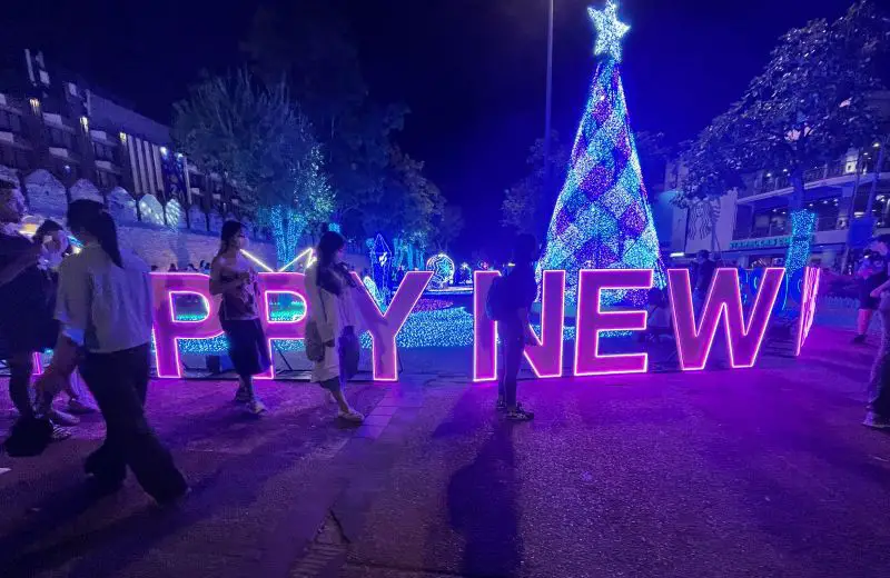 People walking past a purple lit New Year's Eve sign at Chiang Mai, Thailand