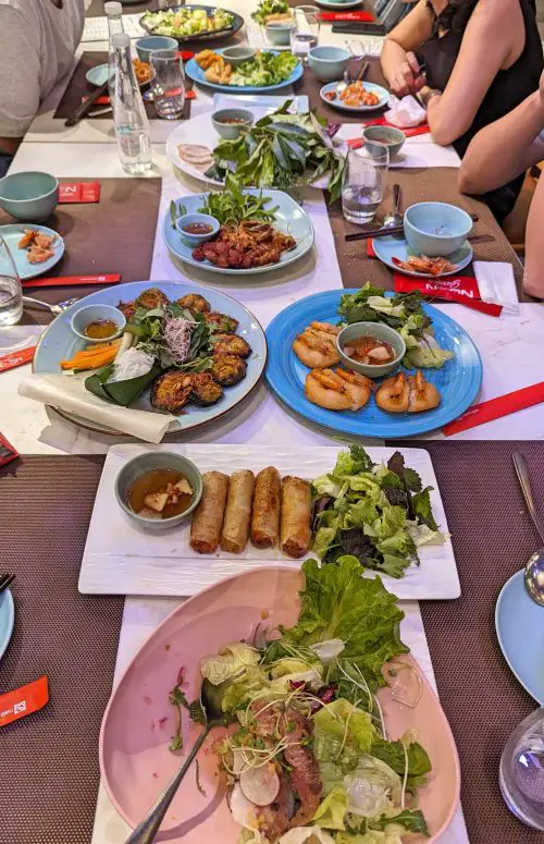 A table with a variety of Vietnamese dishes such as beef salad, fried spring rolls, fried shrimp cakes, fish with vegetables, goat, and more at Ngon Garden in Hanoi