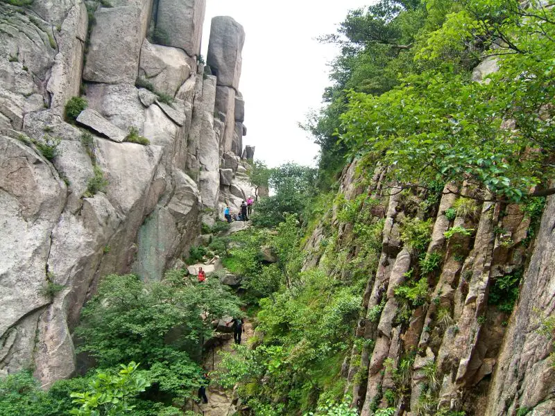 Six hikers going up a hiking path between large rocks and trees at Bukhansan National Park in Seoul, South Korea