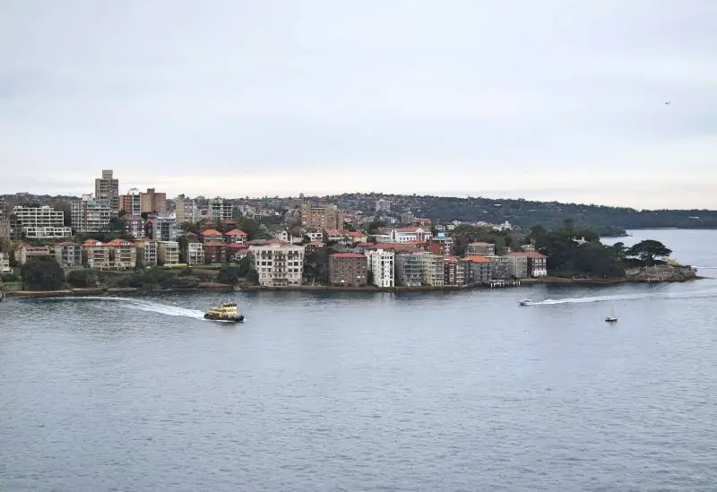 View from Sydney Harbour Bridge of a ferry, two small yachts, apartment buildings along the waterfront