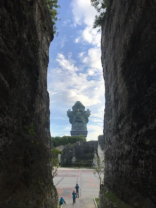 A view of the the tall Garuda Statue between two tall rocks at Garuda Wisnu Kencana Cultural Park in Uluwatu