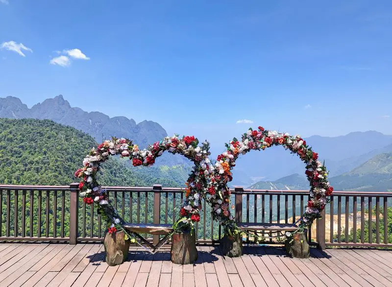 A heart and circle bench with flowers and overlooking the O Quy Ho mountain range in Sapa, Vietnam