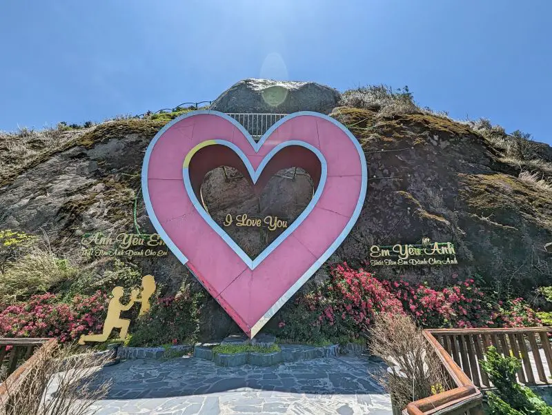 A pink heart sculpture and a gold I Love You sign on the mountain at Heaven Gate O Quy Ho in Sapa, Vietnam