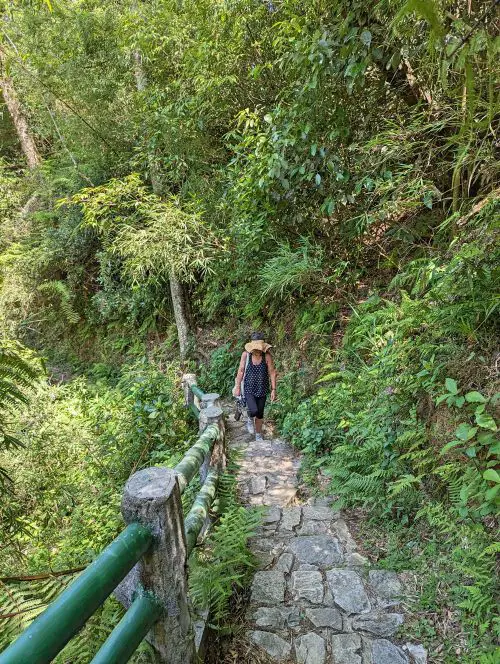 A woman wearing a hat climbing up the stone stairs to reach Love Waterfall, Sapa