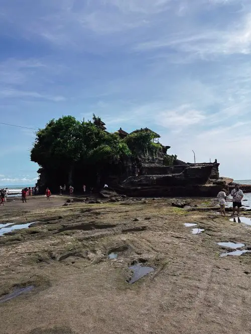 A walking path leads to Tanah Lot Temple at low tide