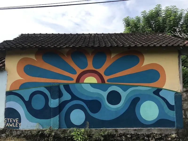 Street art by Steve Fawley in Uluwatu, Bali, with the top half of an orange and blue flower and the bottom half of abstract wave and dots