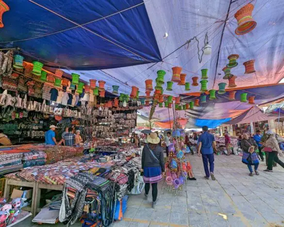 People walking around a plaza and passing by souvenirs items for sale at Bac Ha Market