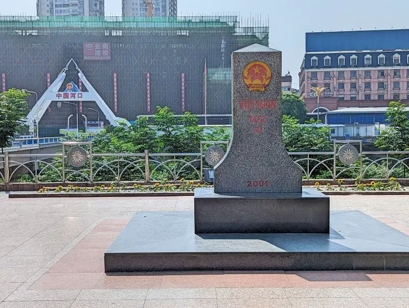 A marble monument that says Vietnam 102 (2), 2001 with the gates to China border in the background