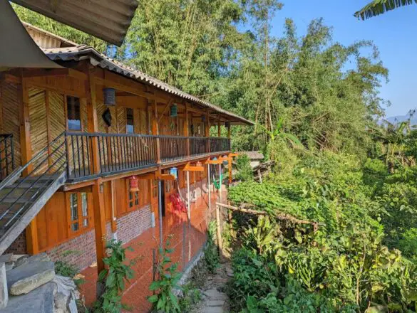 A two story wooden building surrounded by trees at Mama Si Homestay, one of the top homestays in Sapa to stay at