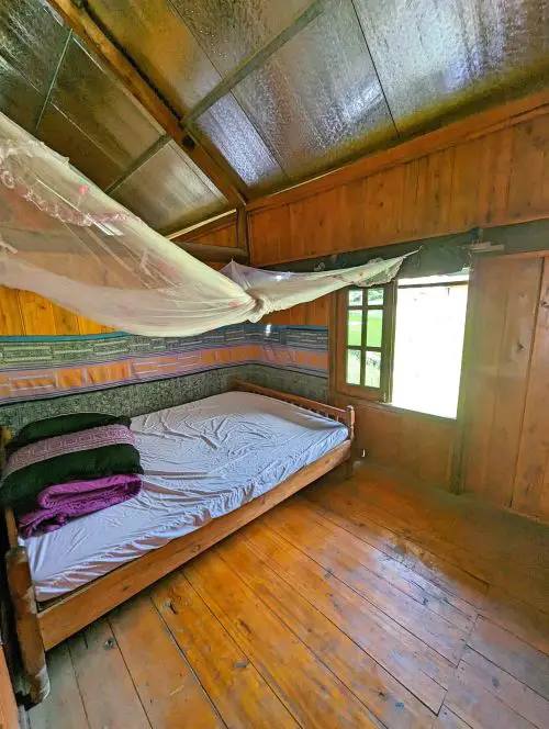 A bed with a purple and black blanket and a mosquito net at May's Homestay in Sapa, Vietnam